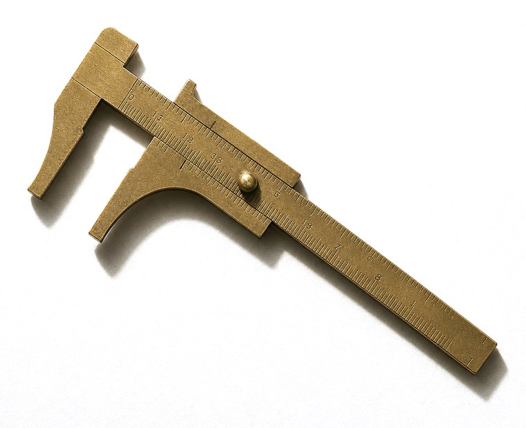 A brass vernier caliper resting on paper